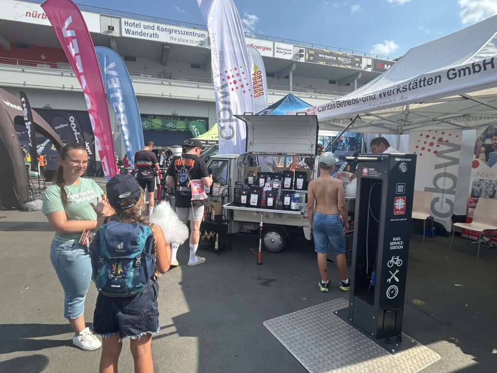 Menschen im Gespräch, Infostand der CBW mit Beachflag, Radservicestation und Kaffeewagen.